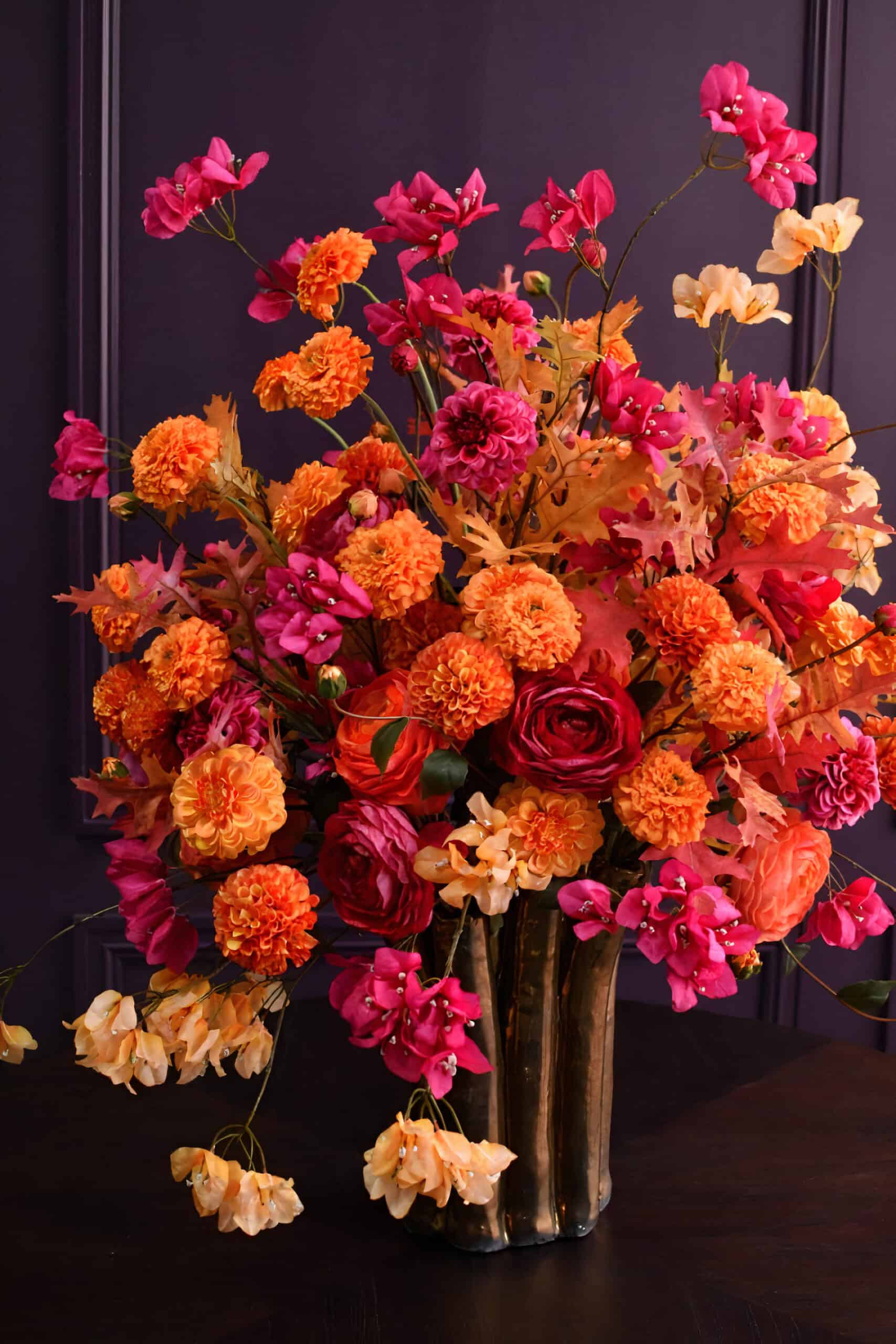 Warm autumn silk flower display featuring Bougainvillea, Ranunculi and Oak leaf perfect for a cosy home.